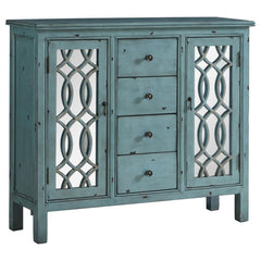 This well-crafted wooden cabinet adds a splash of color and classic charm to any space. Finished in a distressed blue, it features four center drawers for organizing linens or silverware, while two side doors with mirrored insets and carved lattice detail