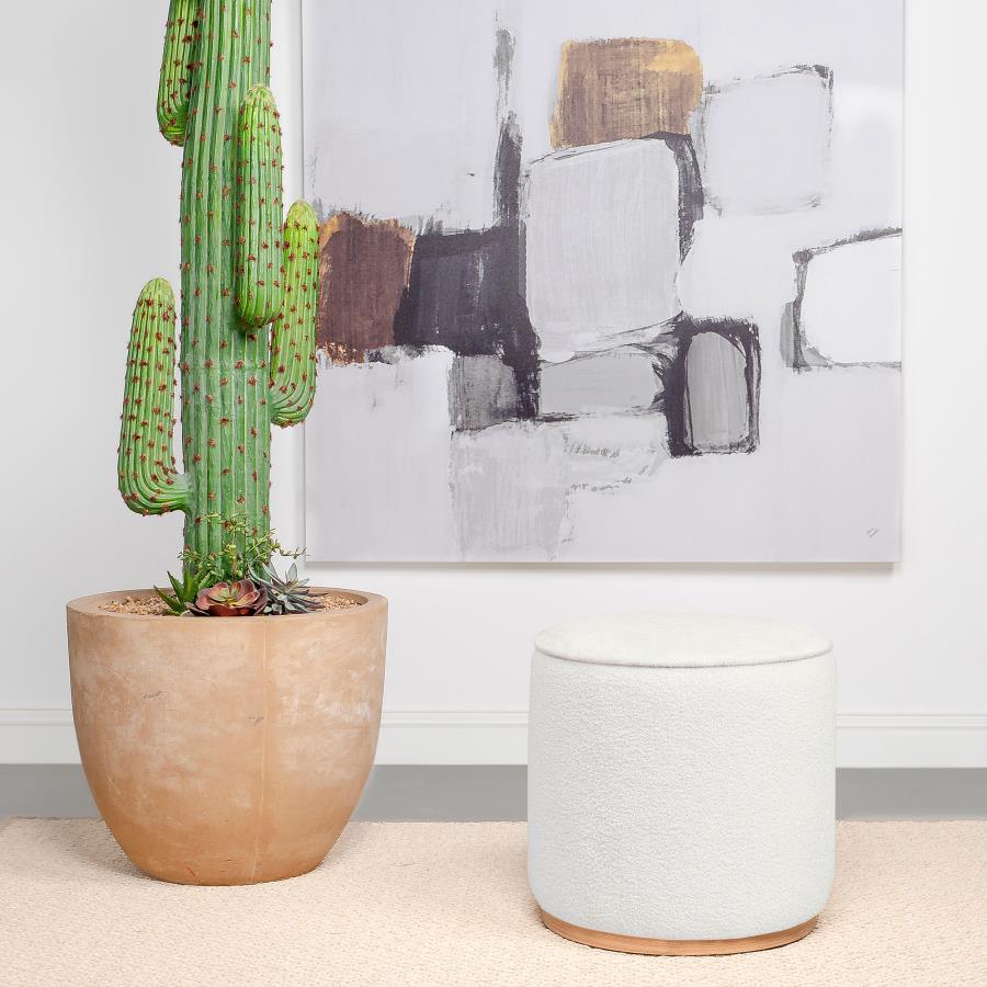 Add a touch of playful luxury to your living space with this round upholstered ottoman, swathed in sumptuous faux sheepskin that invites you to touch. Resting on a metal base that-'s been expertly finished to emulate the warm, natural allure of wood grain