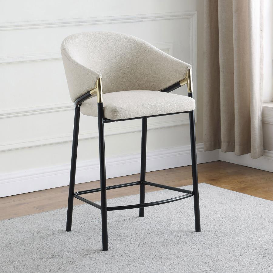 This pair of two stools offer a Hollywood regency look. With a tall and sleek design, the legs come in a glossy black finish that lends to many color palettes and offers a handsome look. Each stool has a cushioned seat, wrapped in a linen-like fabric that