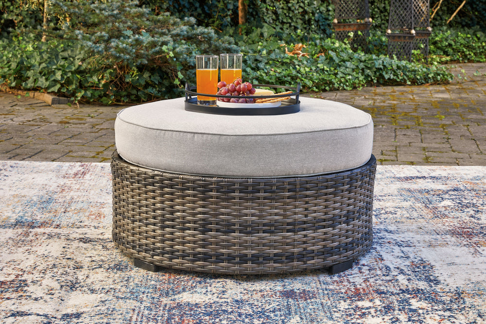 This cool, casual outdoor ottoman will raise the comfort level and visual appeal of your outdoor living space. Made of handwoven wicker in neutral tones of light and dark gray, the cushioned ottoman blends beautifully into your lanai or pool and patio are