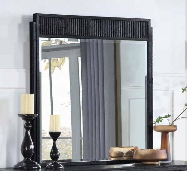 it features a wooden frame complete with a fluted panel on top that adds rich depth and dimension. The mirror features a black finish with wire brushing that creates textural flair.