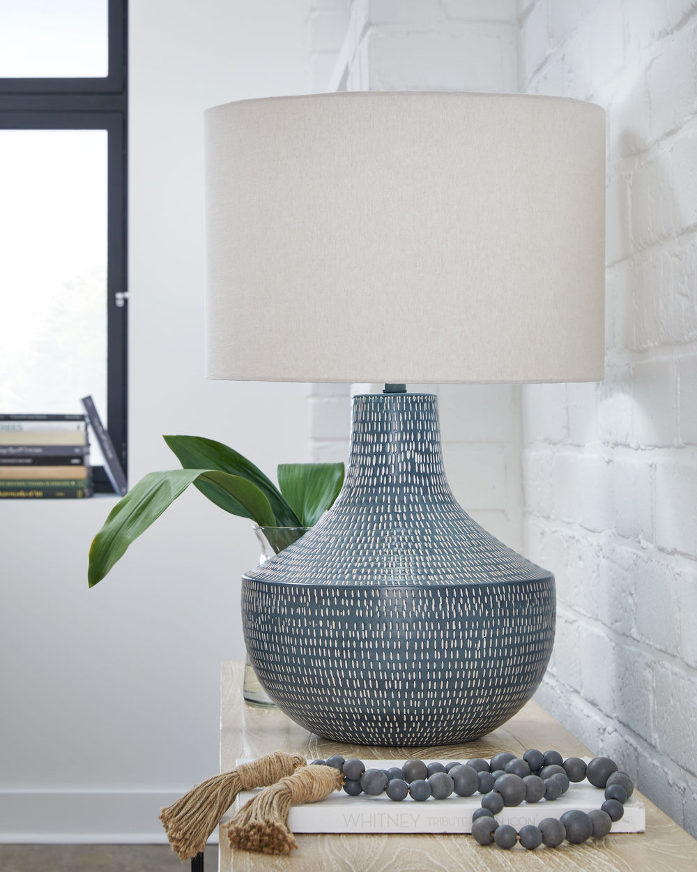 Enhance your decor with a touch of captivating texture. This table lamp features a beautifully crafted body made of hammered metal with an antiqued finish. Topped with a crisp off-white fabric shade, it illuminates a casual vibe with soft, diffused light.
