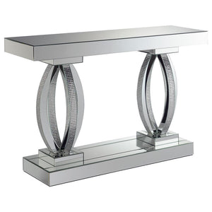 This mirrored console table features an elegant design with a rectangular top and bold, oval-shaped bases. The base is adorned with acrylic crystals, adding a luxurious and glamorous touch to its modern aesthetic. Crafted with mirrored surfaces, this tabl