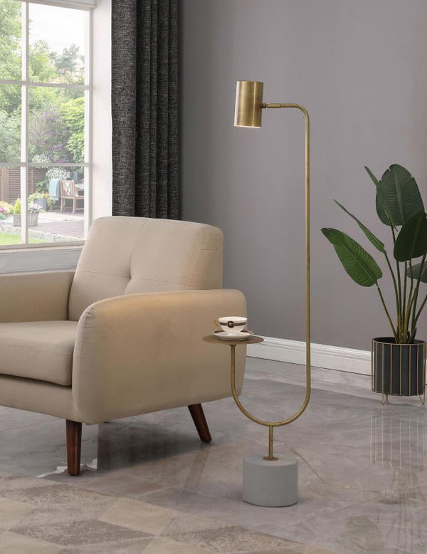  this striking floor lamp presents a slim metal stand situated on a thick cement base. A slender arm in a gleaming antique brass fi