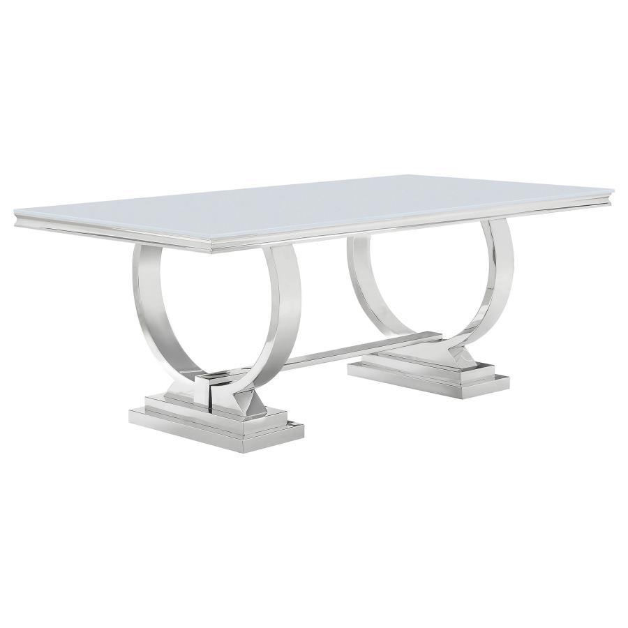 This modern dining table makes a bold statement with its sleek tempered glass top and sculptural stainless steel base. Designed for both elegance and durability, the spacious rectangular surface provides ample room for dining, while the curved trestle des