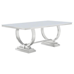 This modern dining table makes a bold statement with its sleek tempered glass top and sculptural stainless steel base. Designed for both elegance and durability, the spacious rectangular surface provides ample room for dining, while the curved trestle des