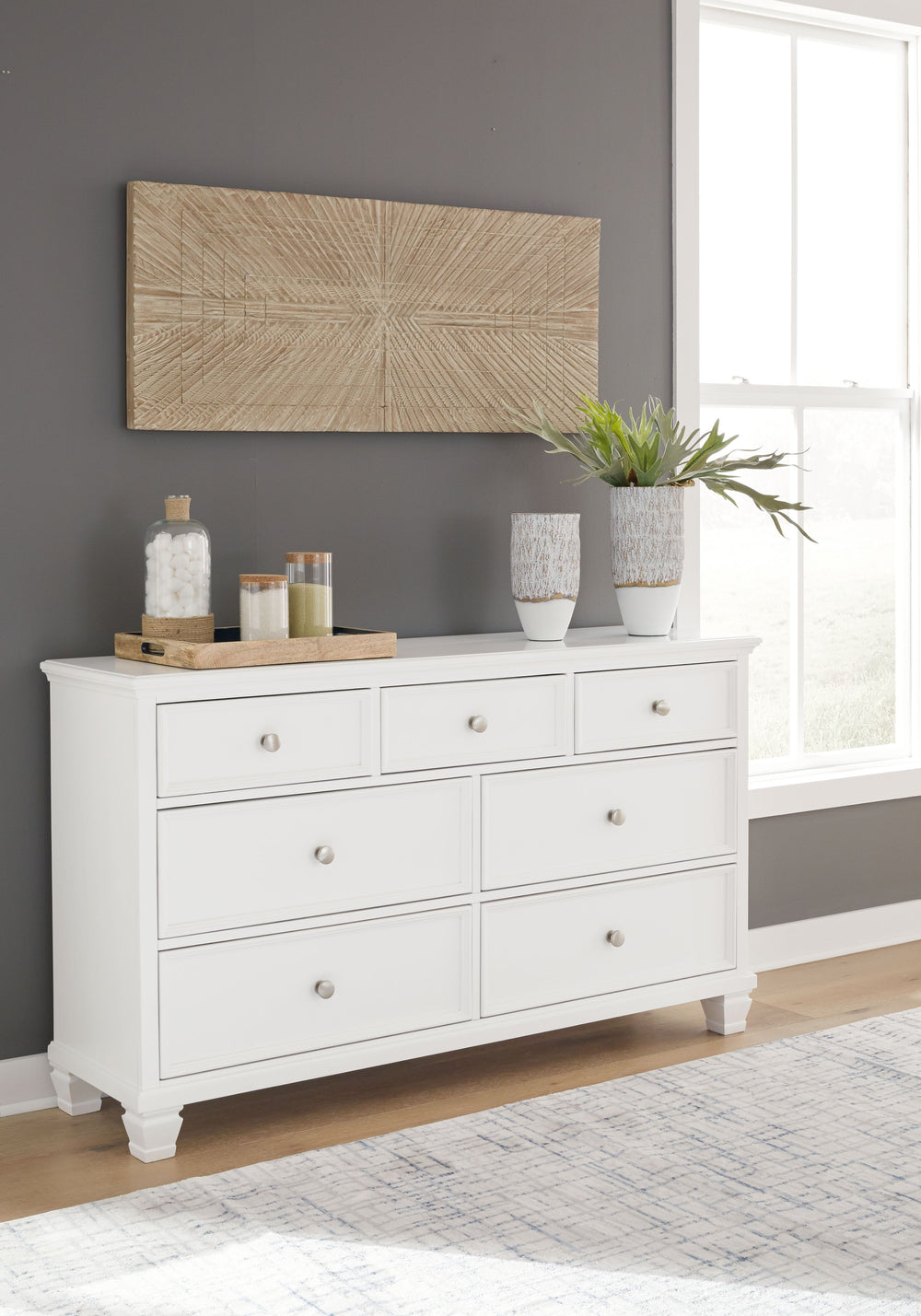 This dresser exudes timeless casual design that-'s ready to define your personal space. Its clean, contemporary white finish, framed drawer fronts and round metal knobs easily adapt to a variety of interiors. Featuring seven storage drawers with dovetail 