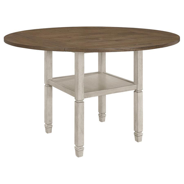 Uniquely fashionable and supremely functional, this counter height dining table has it all. Perfect for spontaneously switching up your style, the square tabletop features four drop down leaves to convert it to a round shape. An open shelf is built into t