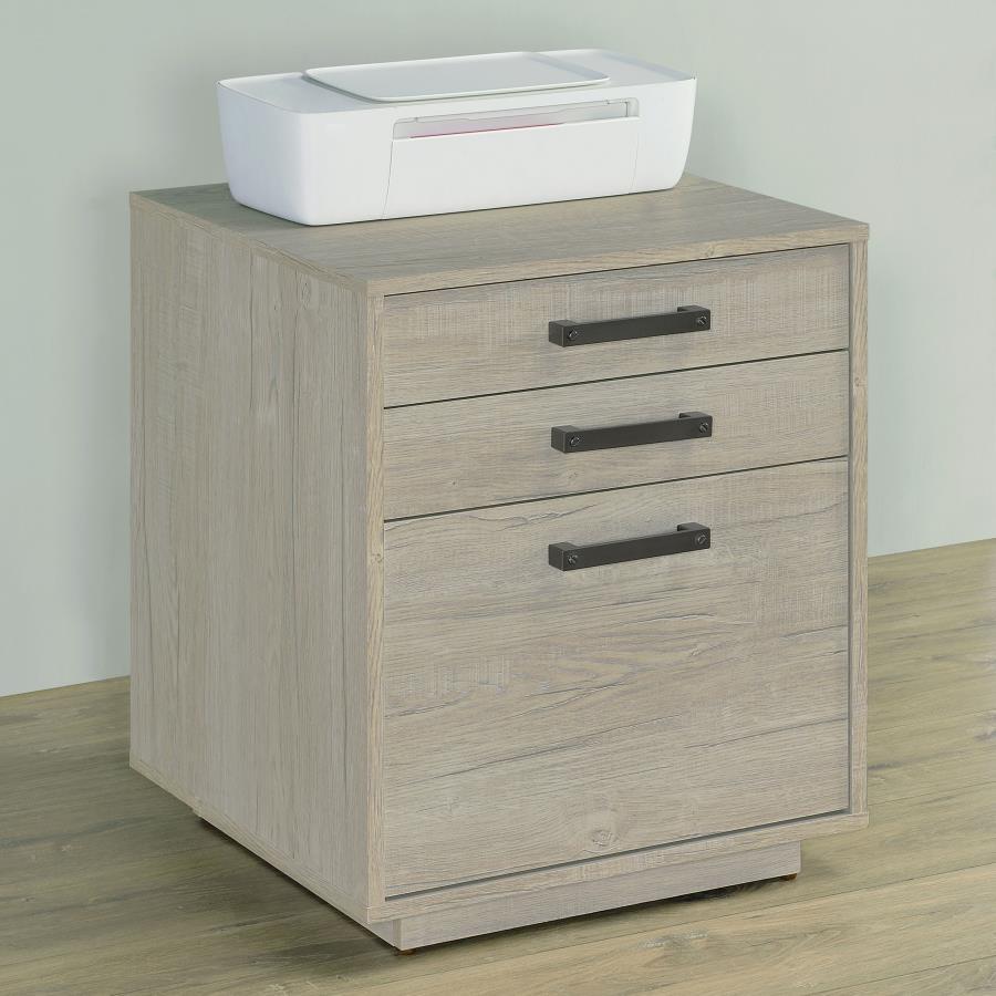 Free up desk space with this contemporary file cabinet, featuring a lovely whitewashed grey finish across its boxy frame and three drawers. Along each drawer is a slim gunmetal finished pull that presents an industrial modern flair to a transitional home 
