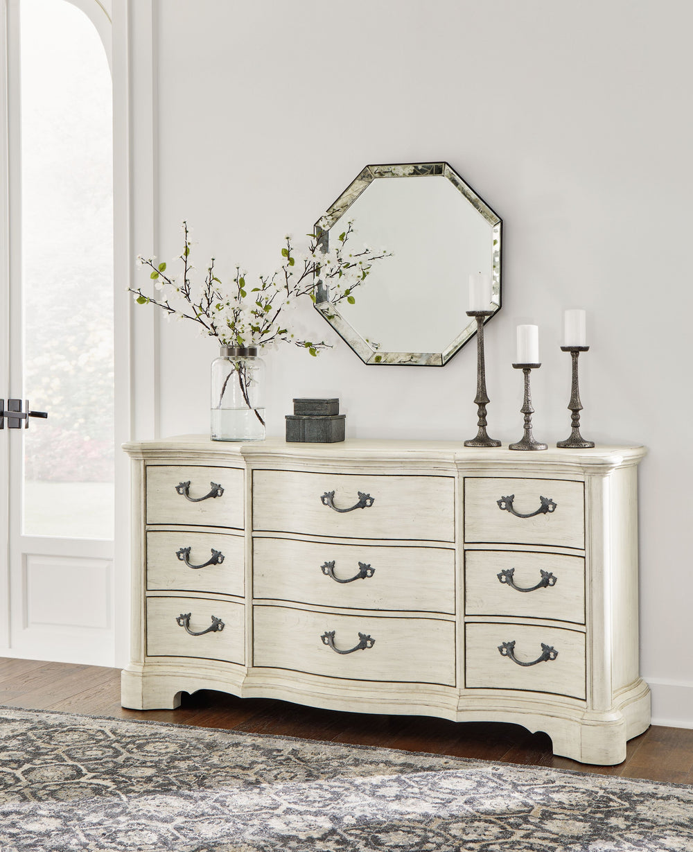Add a touch of romance to your bedroom with this dresser. Its antiqued white painted finish and serpentine-shaped silhouette details are the picture of easy elegance. Drawers in multiple sizes offer ample storage space, while custom-designed bar pulls add