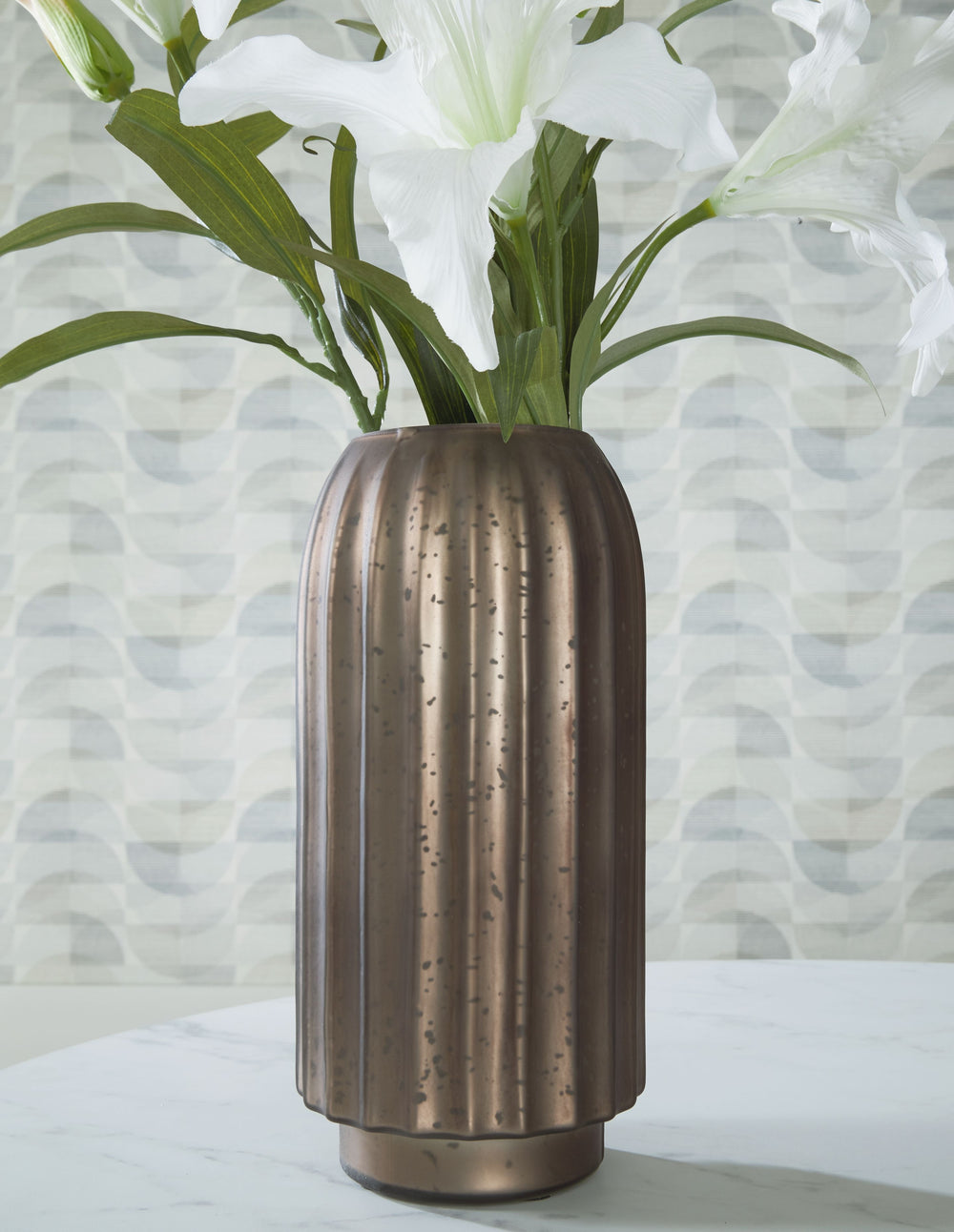 If contemporary style speaks to your design sensibilities, this vase will captivate you with its on-point aesthetics. A stunning mercury glass finish and fluted design make it a visual delight. This exquisite piece effortlessly stands out on its own, or y