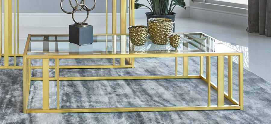 This modern rectangular coffee table features a clear tempered glass top paired with a geometric base made from heavy-gauge metal with a sleek electroplated finish. The open design offers a contemporary aesthetic, blending elegance with durability. Perfec