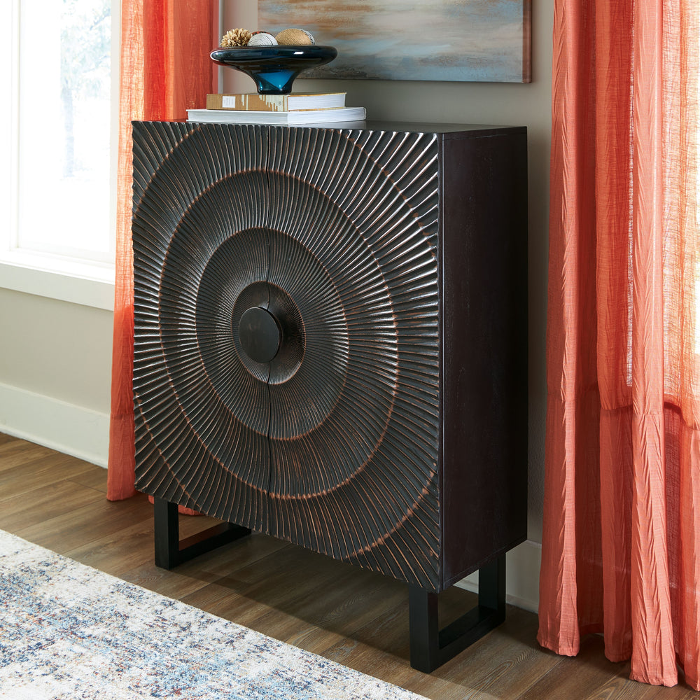 High style is on the rise with this wood accent cabinet. Its stunning doors, graced with a carved sunburst pattern and oversized wood pull, open to reveal two shelves. A distressed black finish adds contemporary flair. Whether this cabinet is accommodatin