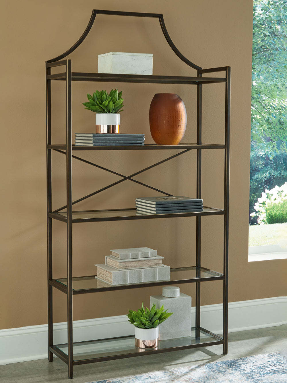 Classic design effortlessly blends with modern functionality in this elegant bookcase. Its antiqued bronze-tone finish adds a touch of warmth and sophistication, while the clear glass shelves create an airy and spacious feel. Itâ€™s exactly what youâ€™ve 