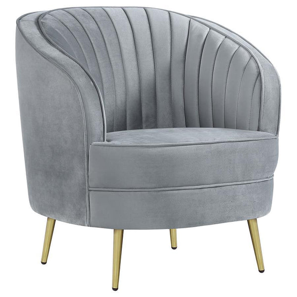 Add a touch of retro-inspired glamour to your space with this elegant accent chair in soft grey velvet. The curved barrel design and channeled backrest create a stylish focal point, while plush cushioning and gold tapered legs provide comfort and modern s