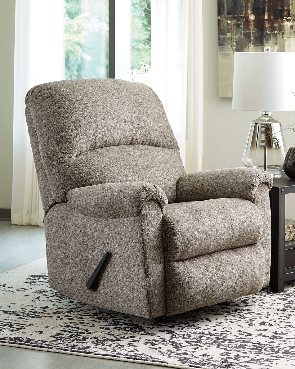A mastery in -"less is more,-" this rocker recliner manages to make cool, contemporary design so warm and cozy. Its soothing platinum-tone upholstery, incredibly plush to the touch, is a new twist on neutral. A curved divided back and a deeply tufted foot