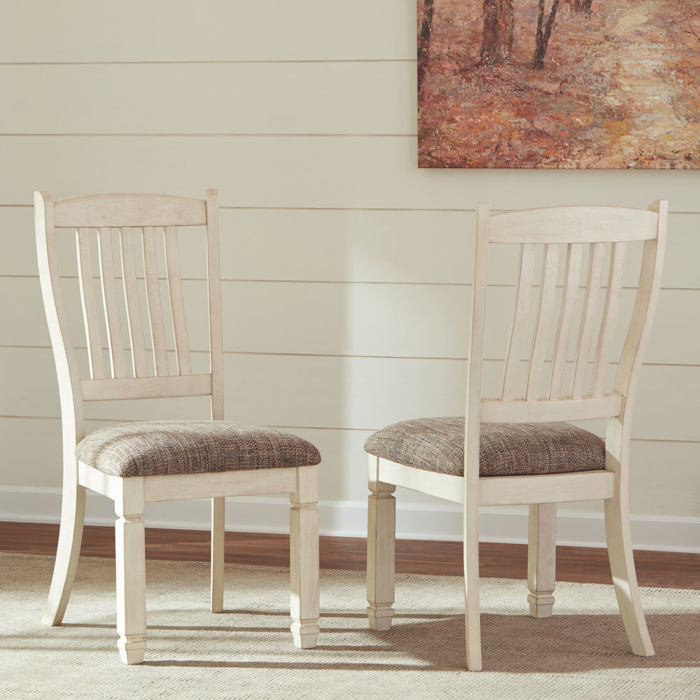 The beauty of this upholstered dining chair is something to savor. Designed to serve up comfort and flair, this rake-back dining chair entices with a cushioned seat covered in a heavy woven fabric that complements the chairâ€™s antiqued white finish.<br><