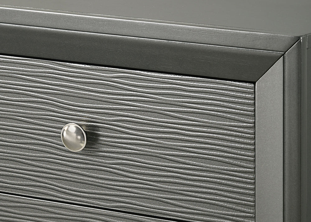 This bedroom collection is the embodiment of sleek, contemporary design, characterized by its rich gunmetal finish and distinctive textured front panels. The centerpiece, a chic bed with a statement headboard, features geometric paneling that adds depth a