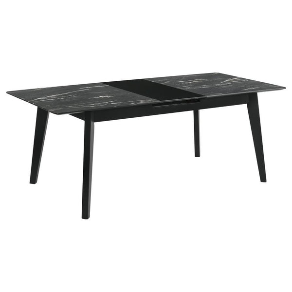 The luxurious look of faux marble creates a glam sensibility for a modern dining table. The black marble look of the tabletop complements a sleek base with fin-style legs and a recessed apron. The table includes a self-storing leaf for easy expansion to a