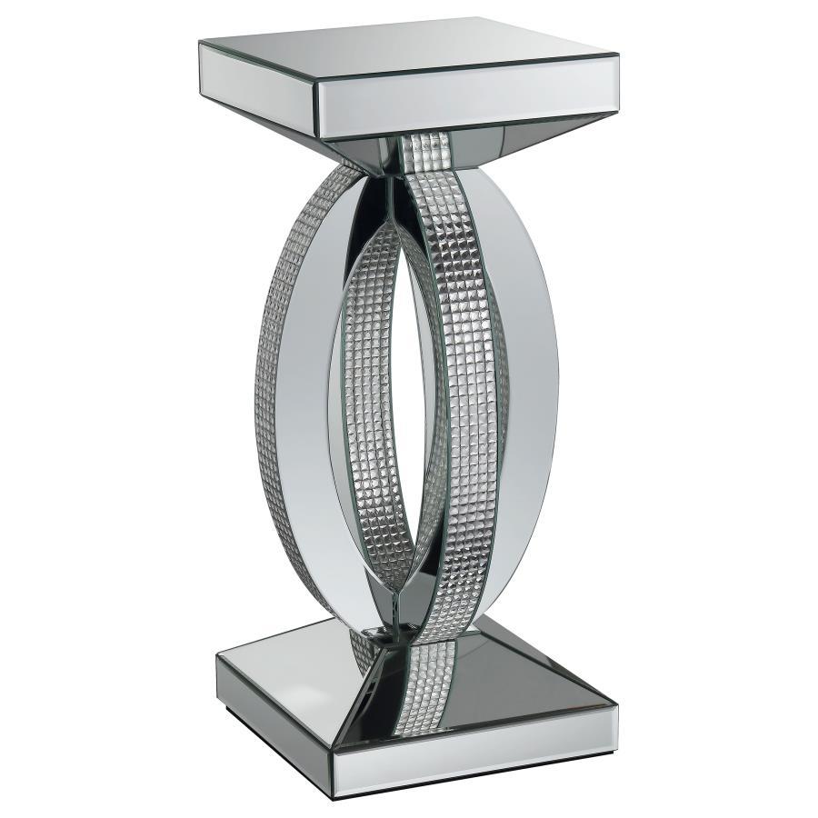 This chic and contemporary end table captivates with its sculptural, artistic design. Crafted with mirrored surfaces and engineered wood, it exudes modern luxury. The intersecting oval-shaped loops form a striking, three-dimensional silhouette, enhanced b