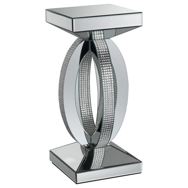 This chic and contemporary end table captivates with its sculptural, artistic design. Crafted with mirrored surfaces and engineered wood, it exudes modern luxury. The intersecting oval-shaped loops form a striking, three-dimensional silhouette, enhanced b