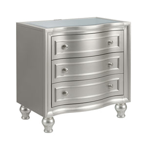 Introducing the Reflection Nightstand in Silver, expertly crafted from solid Pine and high-quality manufactured wood to ensure enduring strength and durability. Its glamorous matte silver finish exudes sophistication, accentuating the mirrored top and sil