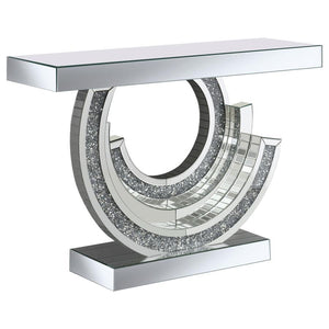 Make a dramatic statement with this glitzy mirrored console table, designed to dazzle from every angle. Its curved, swirl-inspired base creates a stunning three-dimensional look, adorned with smoke grey faux gemstones for extra sparkle. A mirrored tableto